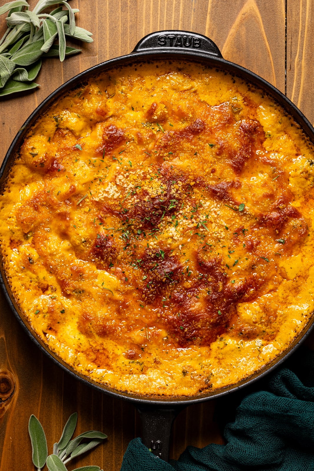 Baked gnocchi in a black skillet on a brown wooden table. 