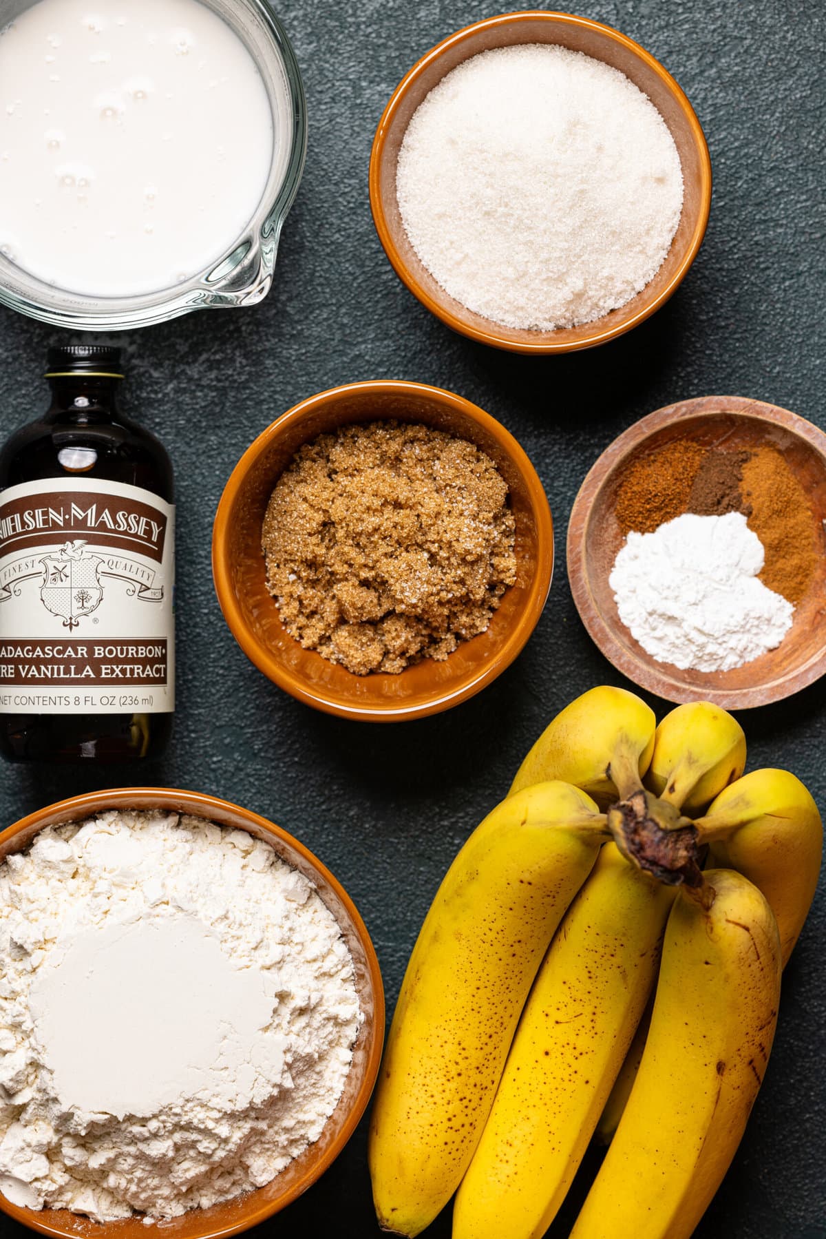 Ingredients for 1 layer banana cake recipe on dark green table.