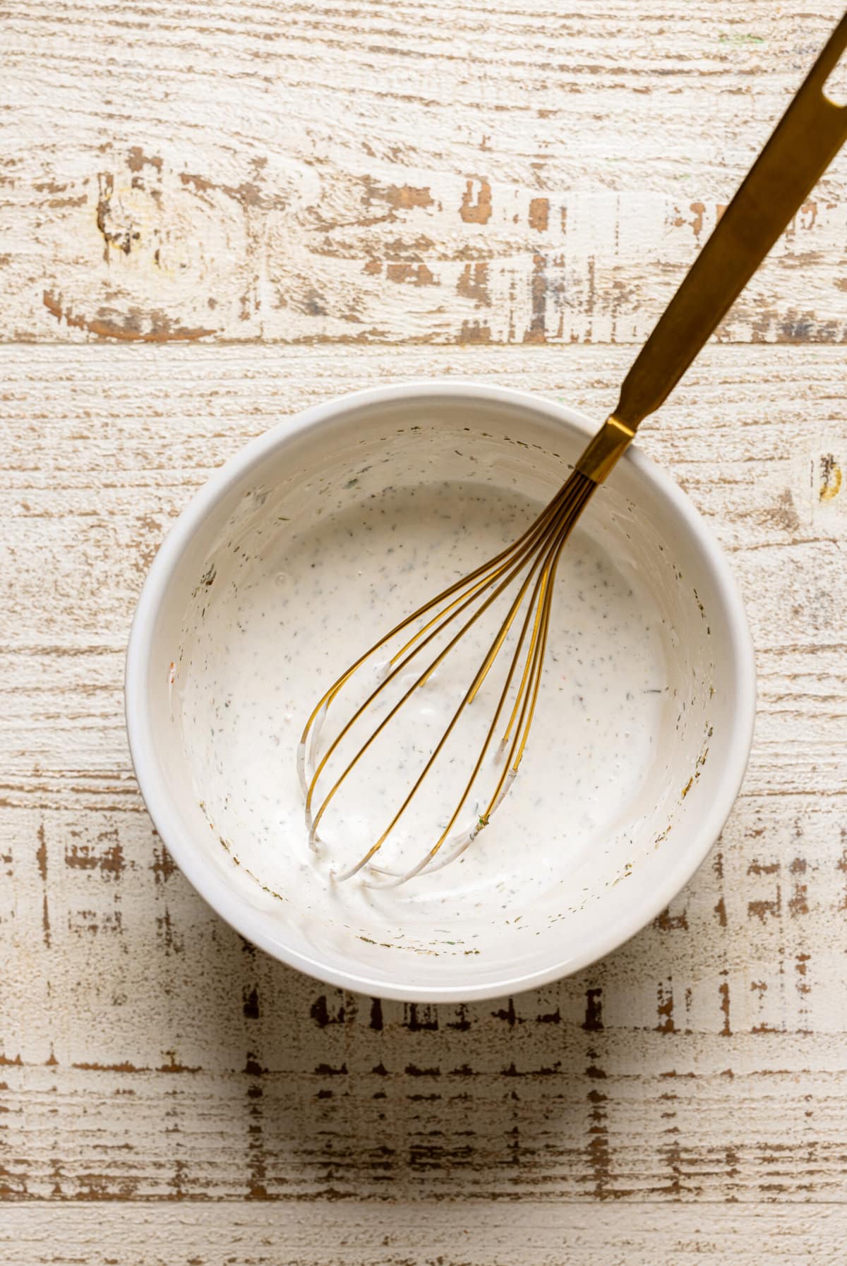 Vegan ranch sauce in a bowl with a whisk.