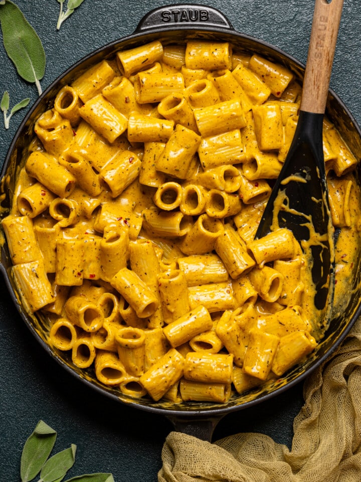 Creamy pasta in a black skillet with a black spoon.