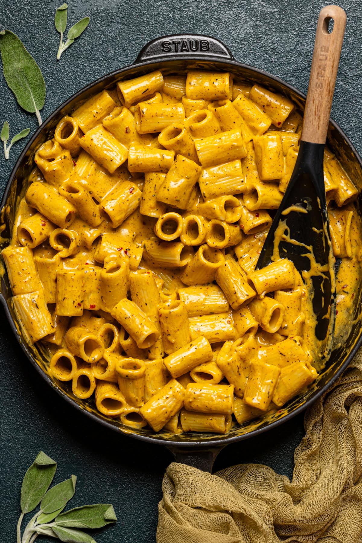 Creamy pasta in a black skillet with a black spoon.