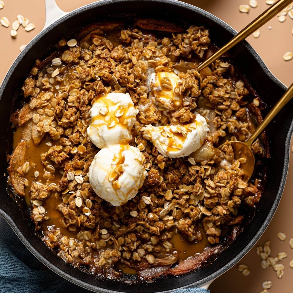 Crisp with ice cream topping and two spoons with oats in a bowl.
