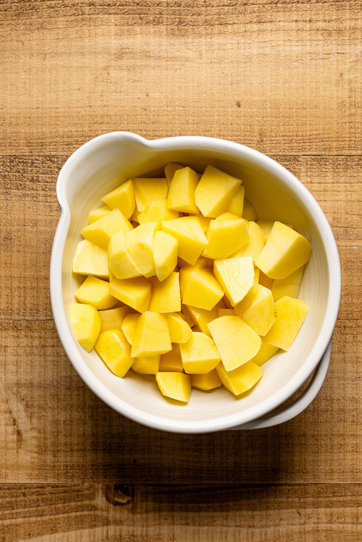 Cubed potatoes in a white bowl. 