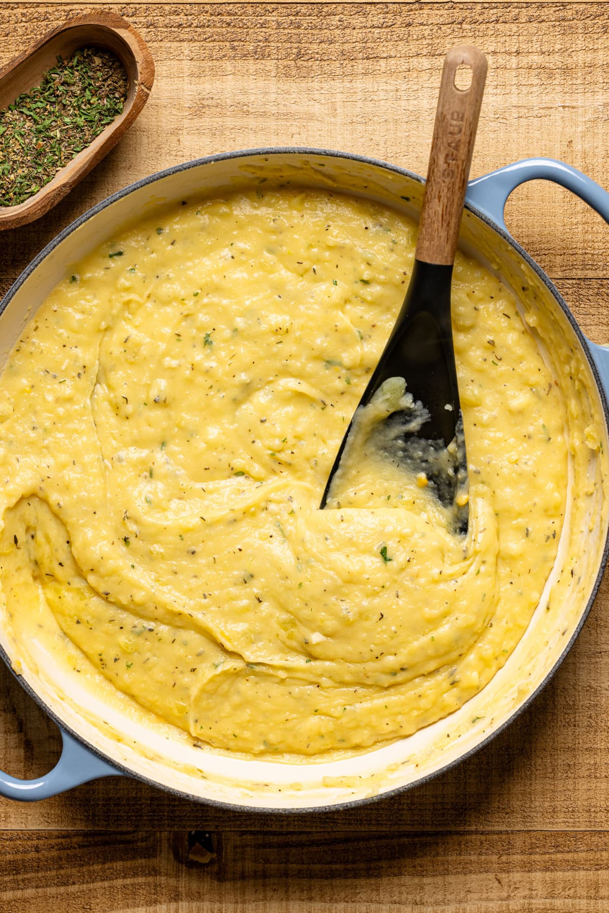 Creamy mashed potatoes in a blue pot with a black spoon. 