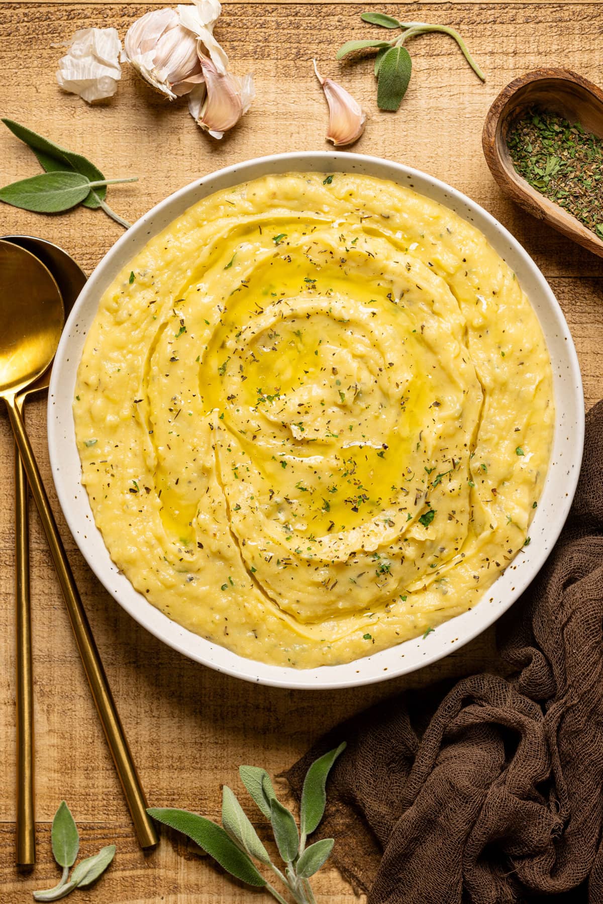 Mashed potatoes in a bowl with a side of two spoons and garnish.