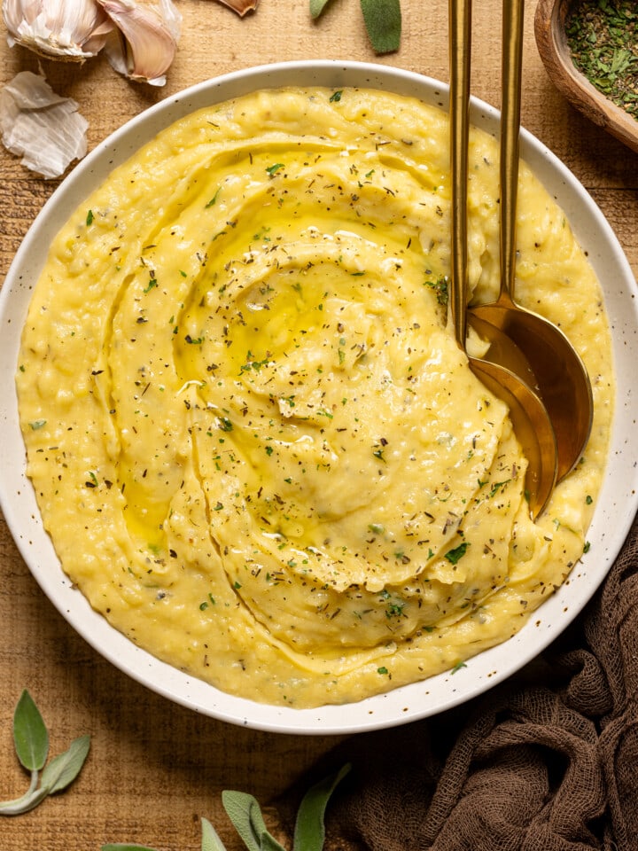 Mashed potatoes in a bowl with two gold spoons and garnish.