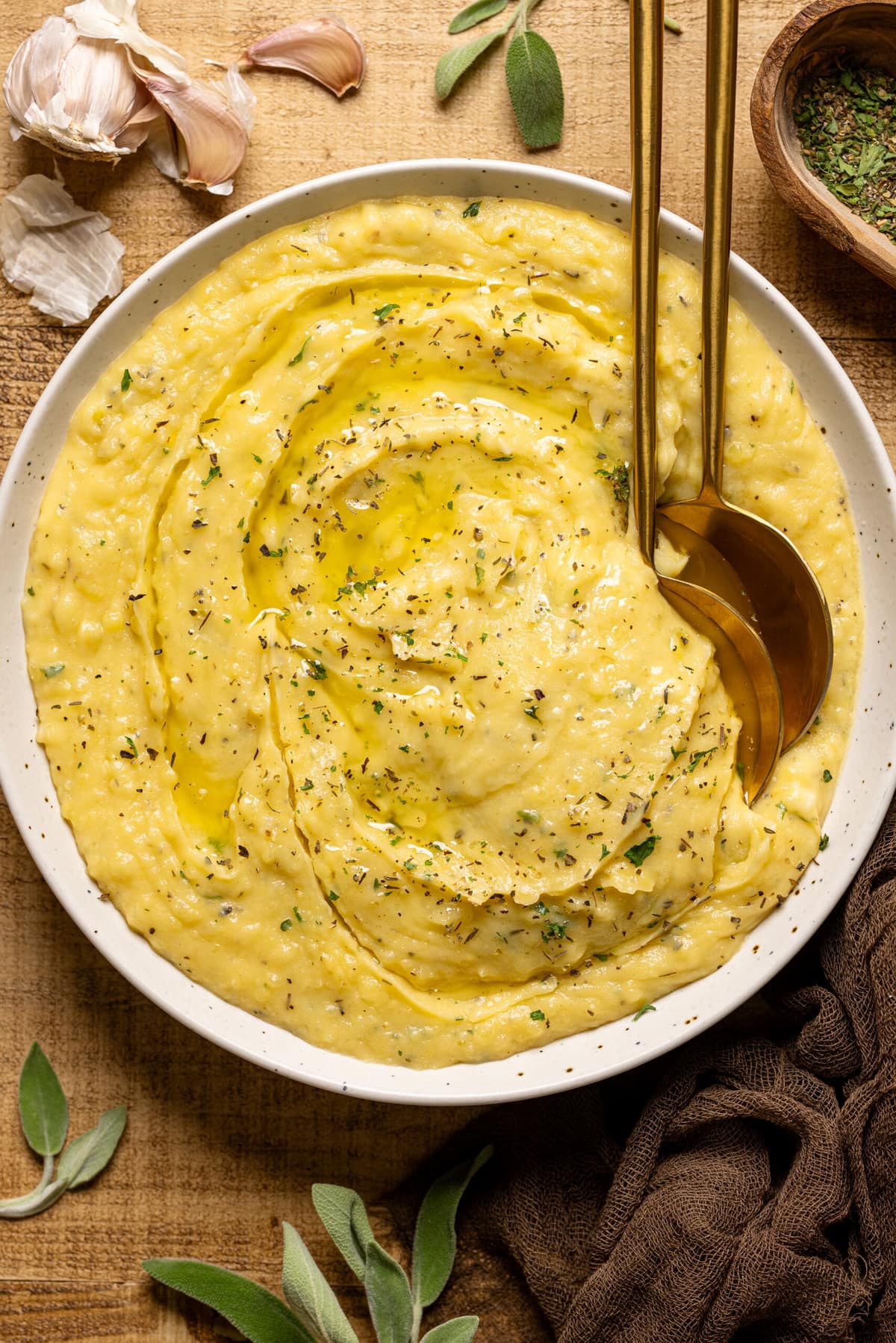 Mashed potatoes in a bowl with two gold spoons and garnish.