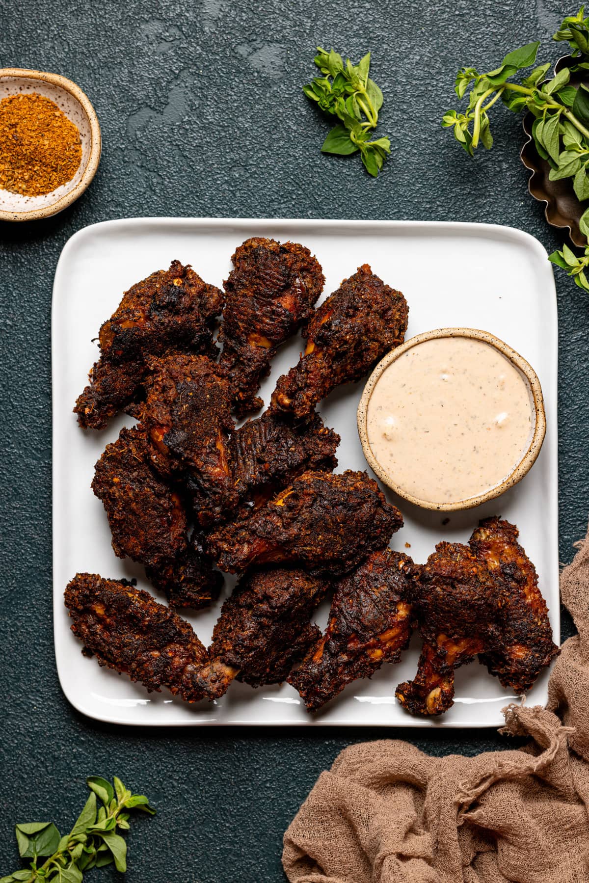 Chicken wings on a white plate with dipping sauce.