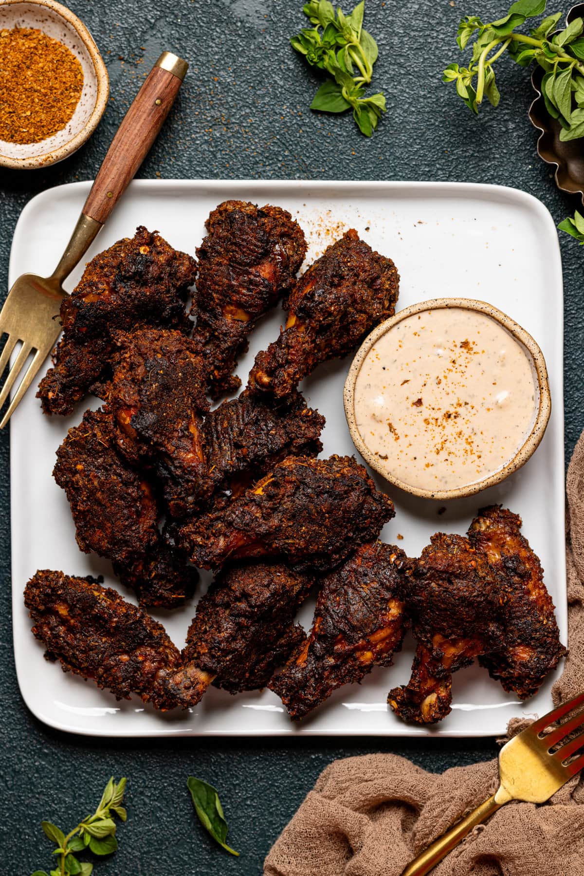 Wings on a white plate with dipping sauce and two forks.