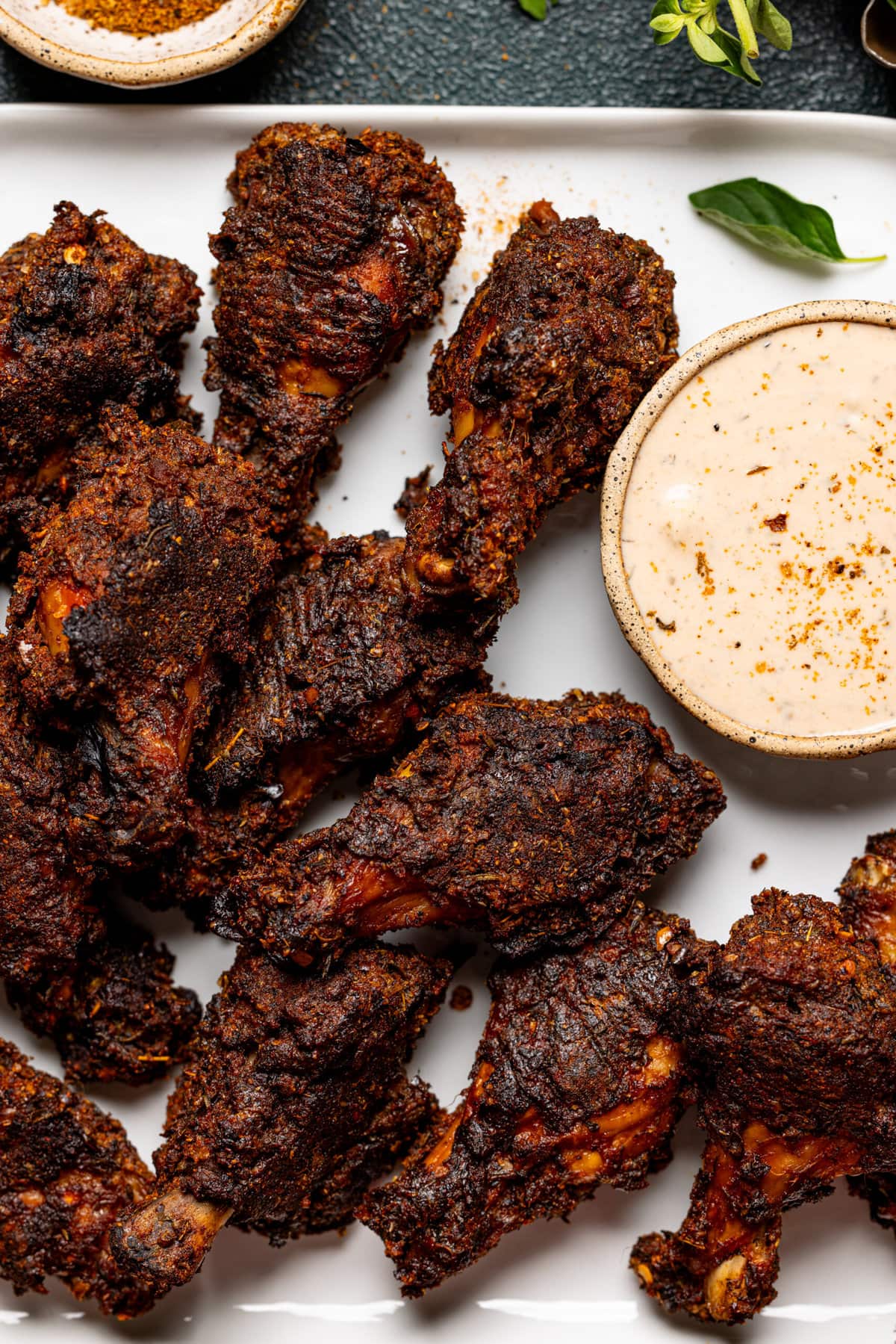 Up close shot of chicken wings on a white plate and dipping sauce.