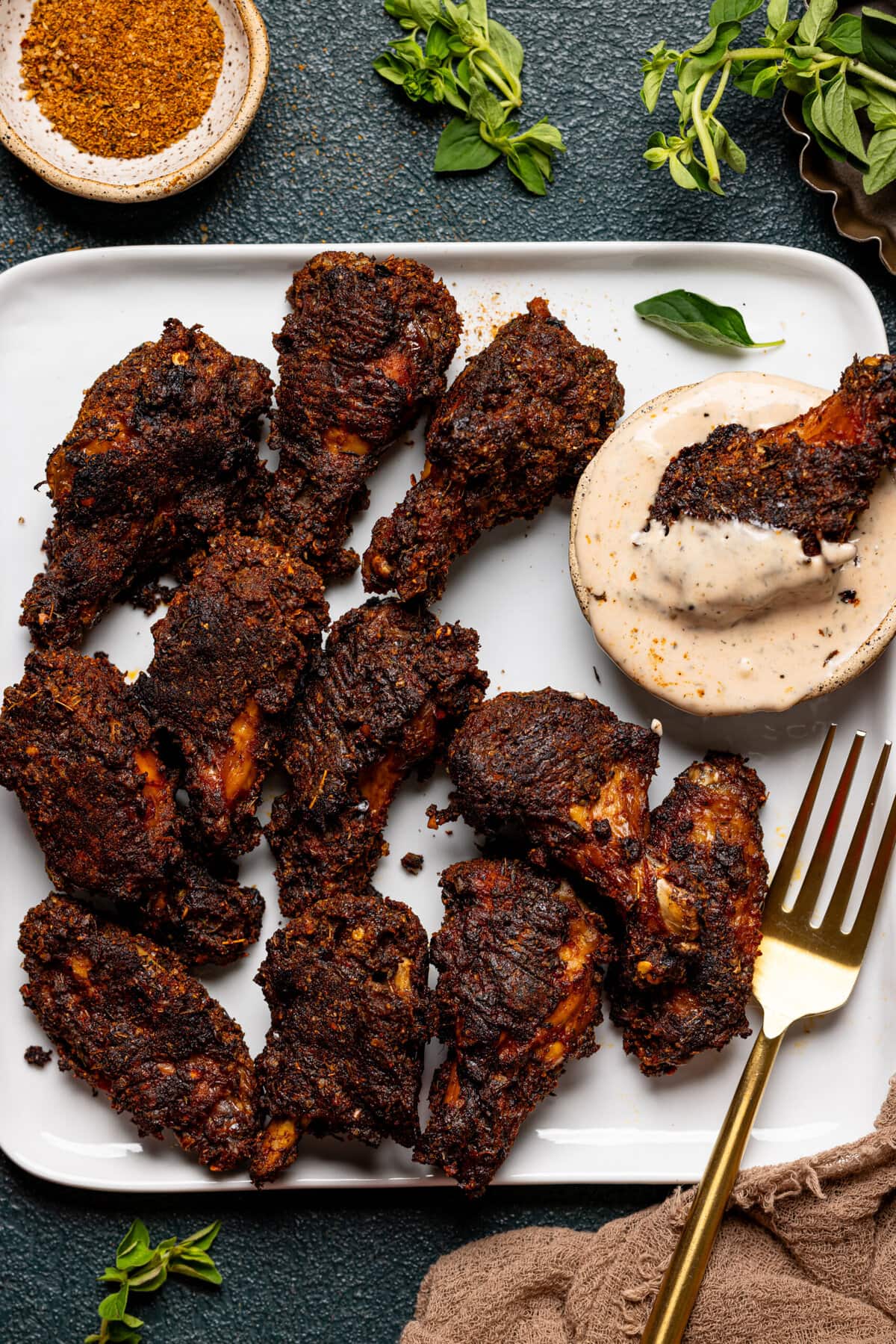 Wings on a white plate with a dipping sauce and fork.