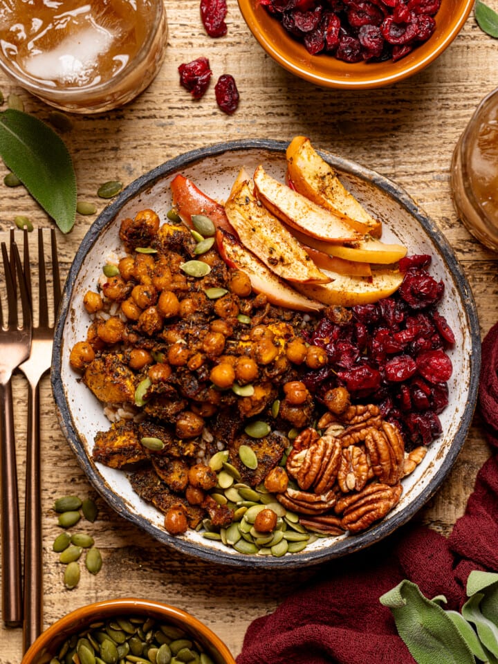 Up close shot of food bowl with two forks, glass of drink, and bowls of ingredients.