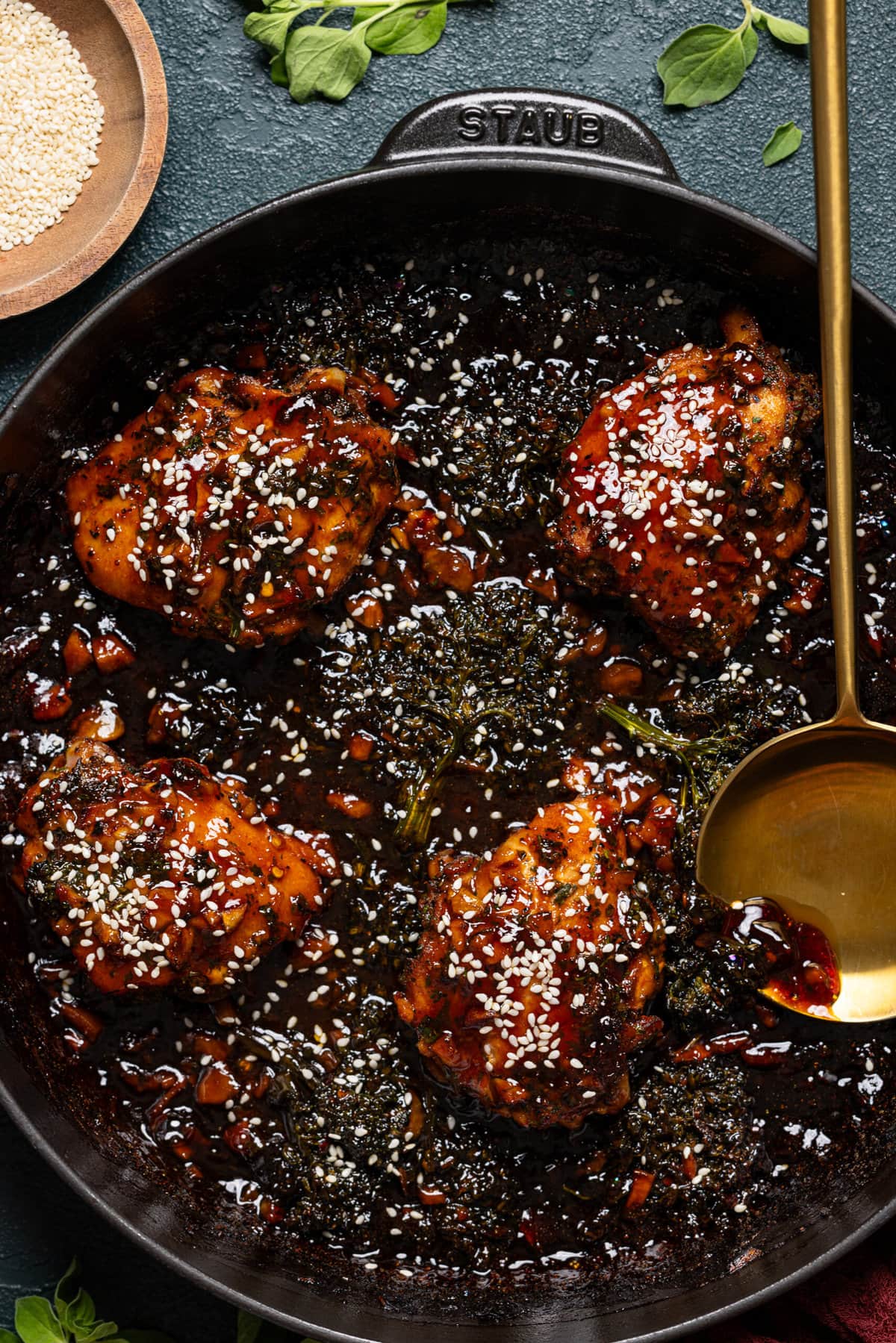 Baked chicken in black skillet with a gold serving spoon. 