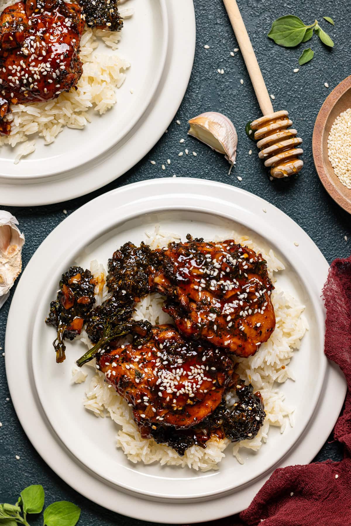 Chicken thighs and rice in two whit plates on a dark green table.