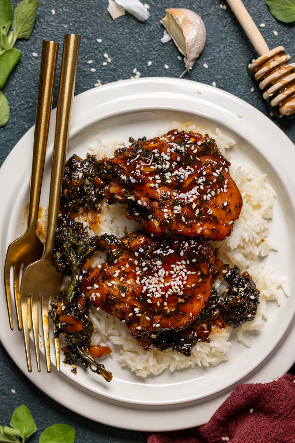 Up close shot of baked chicken and rice in a white plate with two forks.