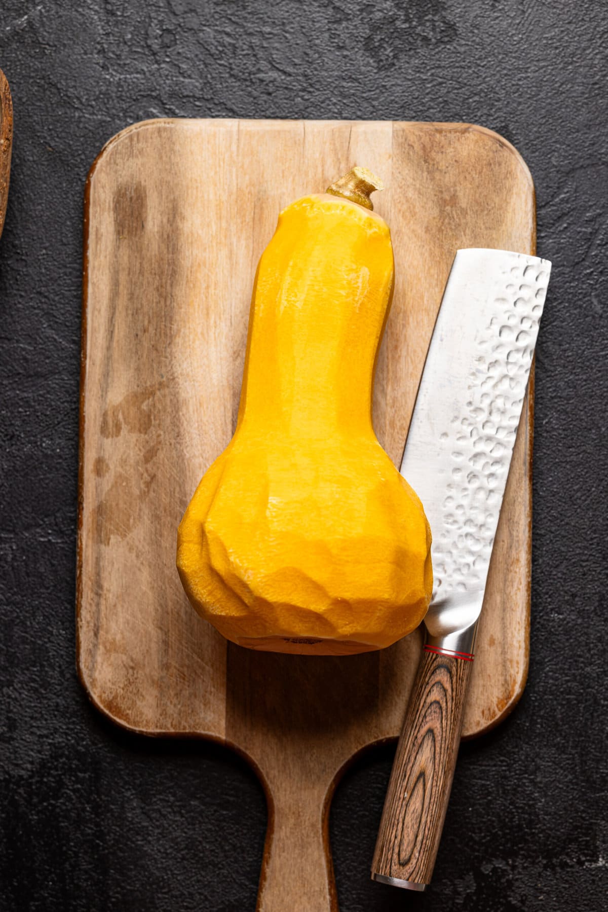 Peeled butternut squash on a cutting board with a knife. 