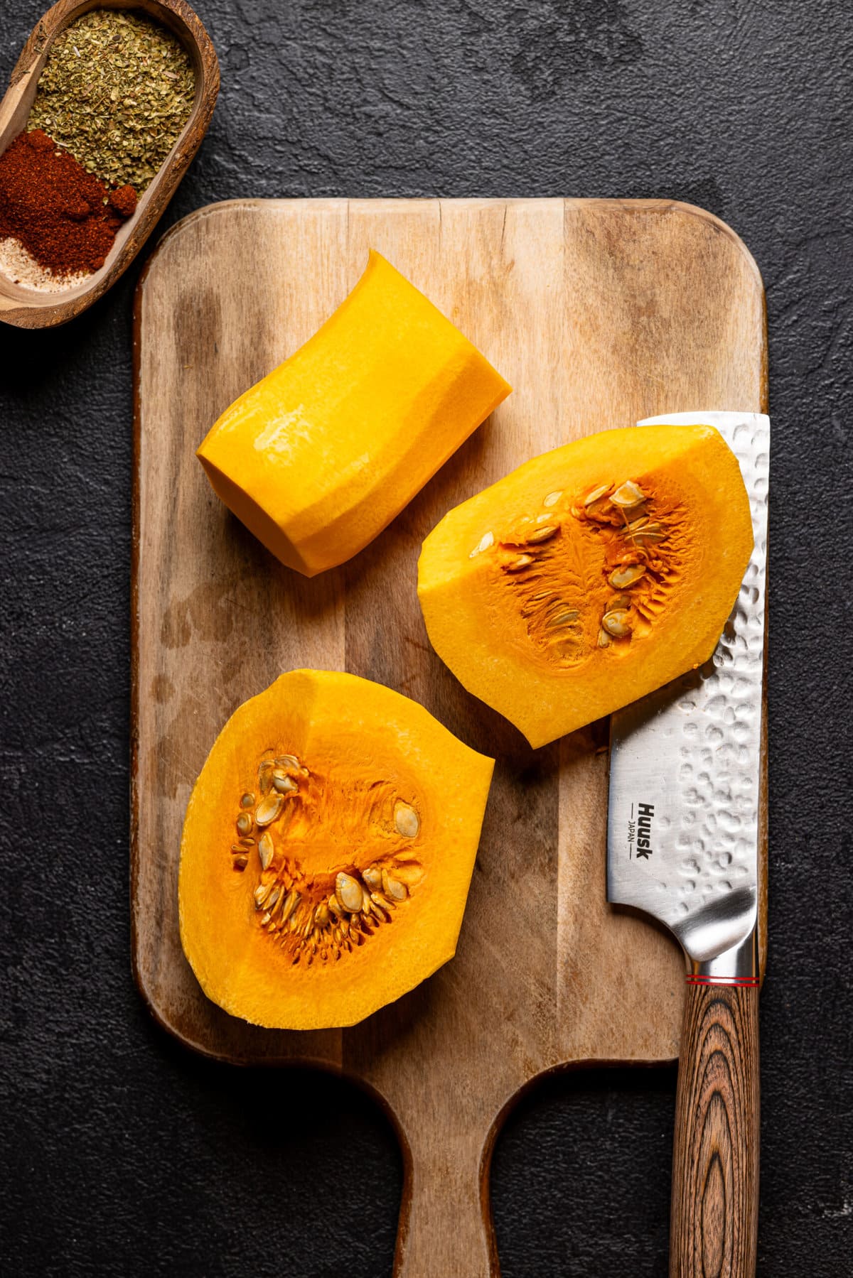 Cut butternut squash on a cutting board with a knife.