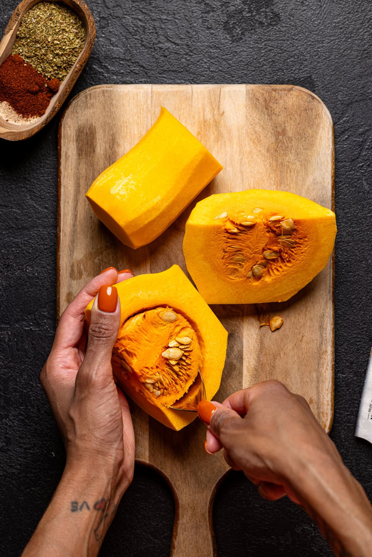 Seeds + core of butternut squash being scooped out and removed. 