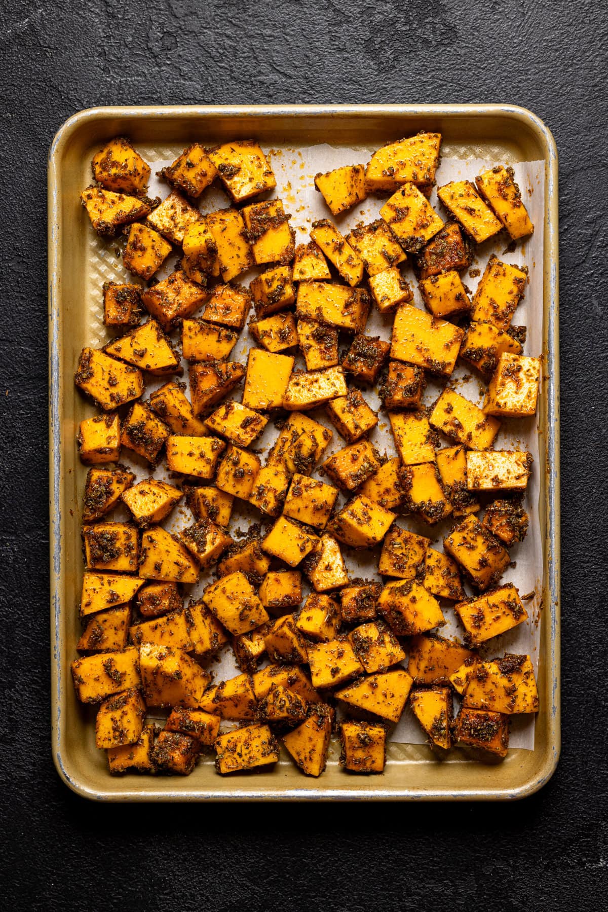 Coated butternut squash on a baking sheet. 