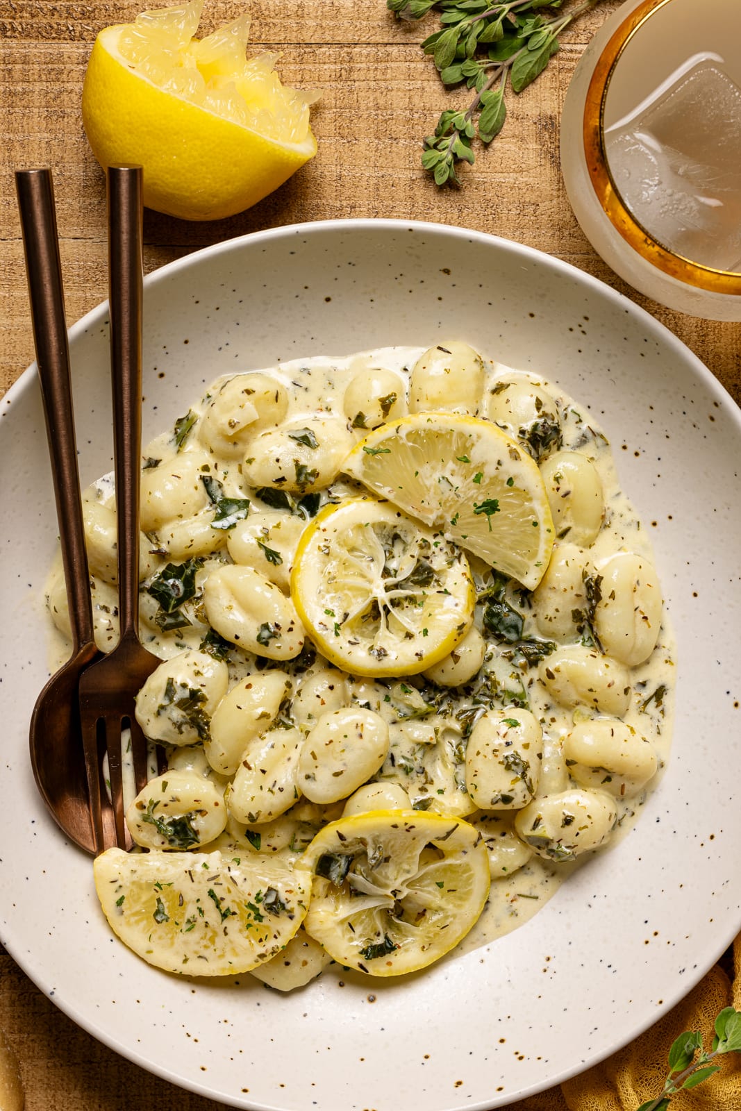 Up close shot of gnocchi in a white plate with fork + spoon.