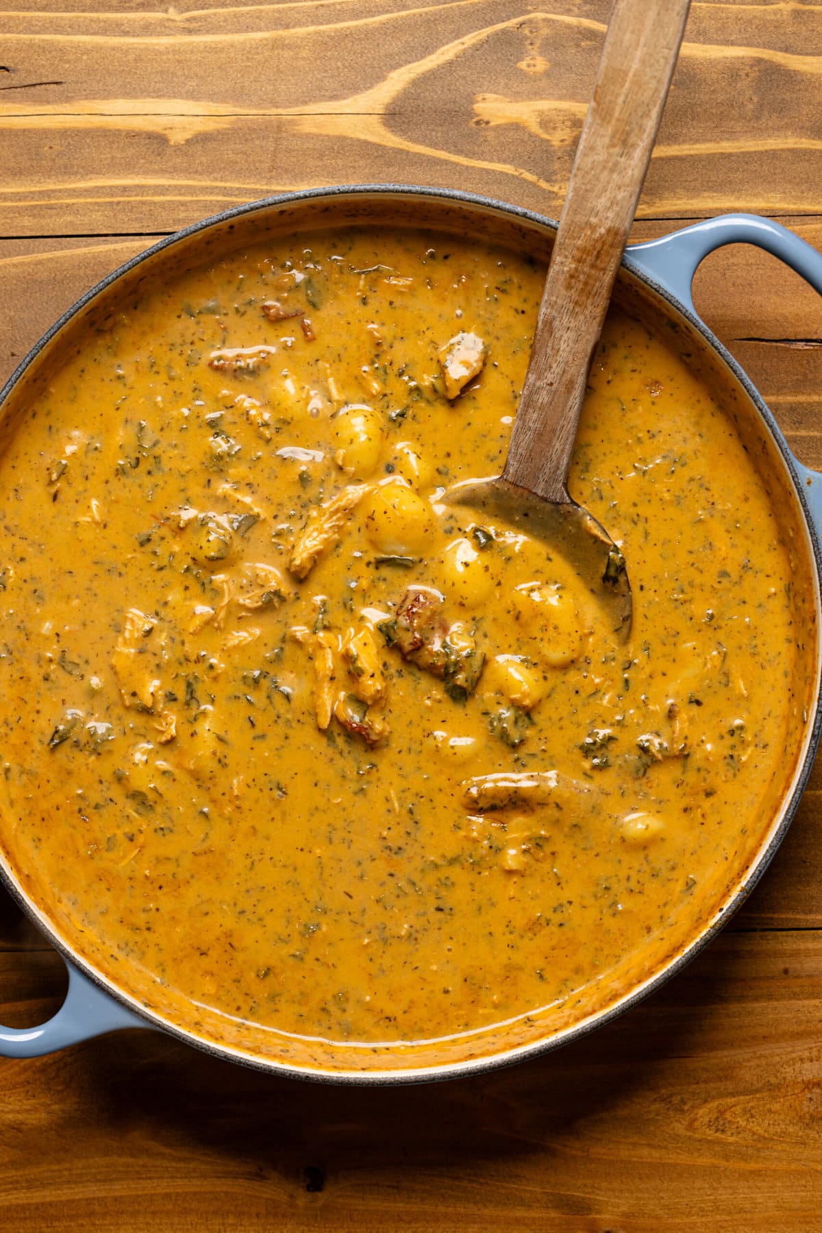 Soup in a large blue pot with wooden spoon.