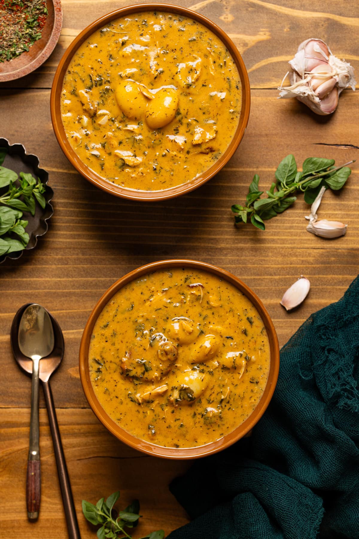 Two bowls of soup with two spoons and garnish.