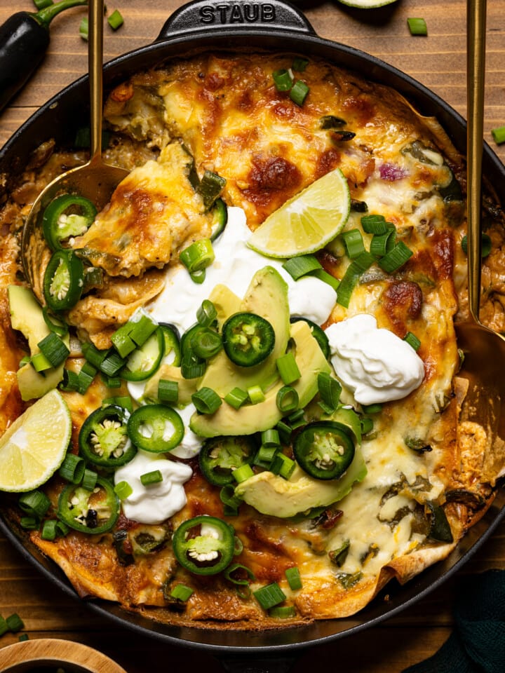 Up close shot of enchilada with two gold spoons and toppings.