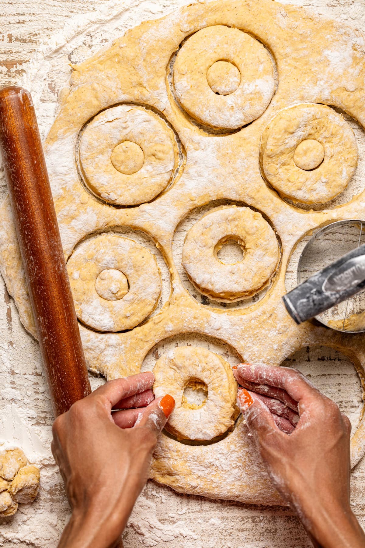 Bagel dough being cut out using a tool.