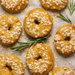 Baked bagels on a baking dish with parchment paper and herbs.