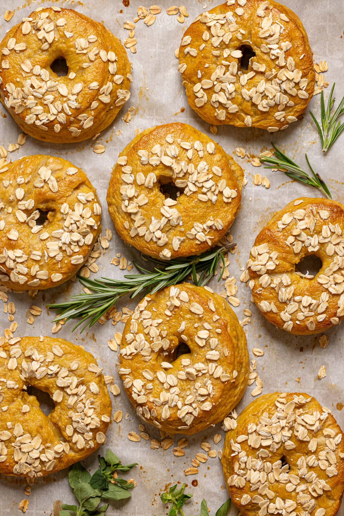Baked bagels on a baking dish with parchment paper and herbs.