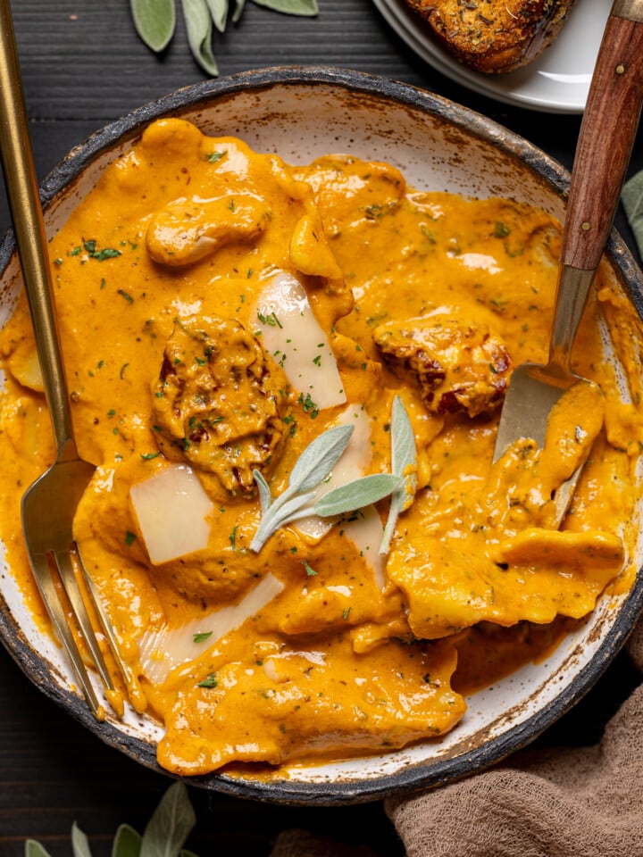 Up close shot of creamy ravioli in a low bowl with two forks.