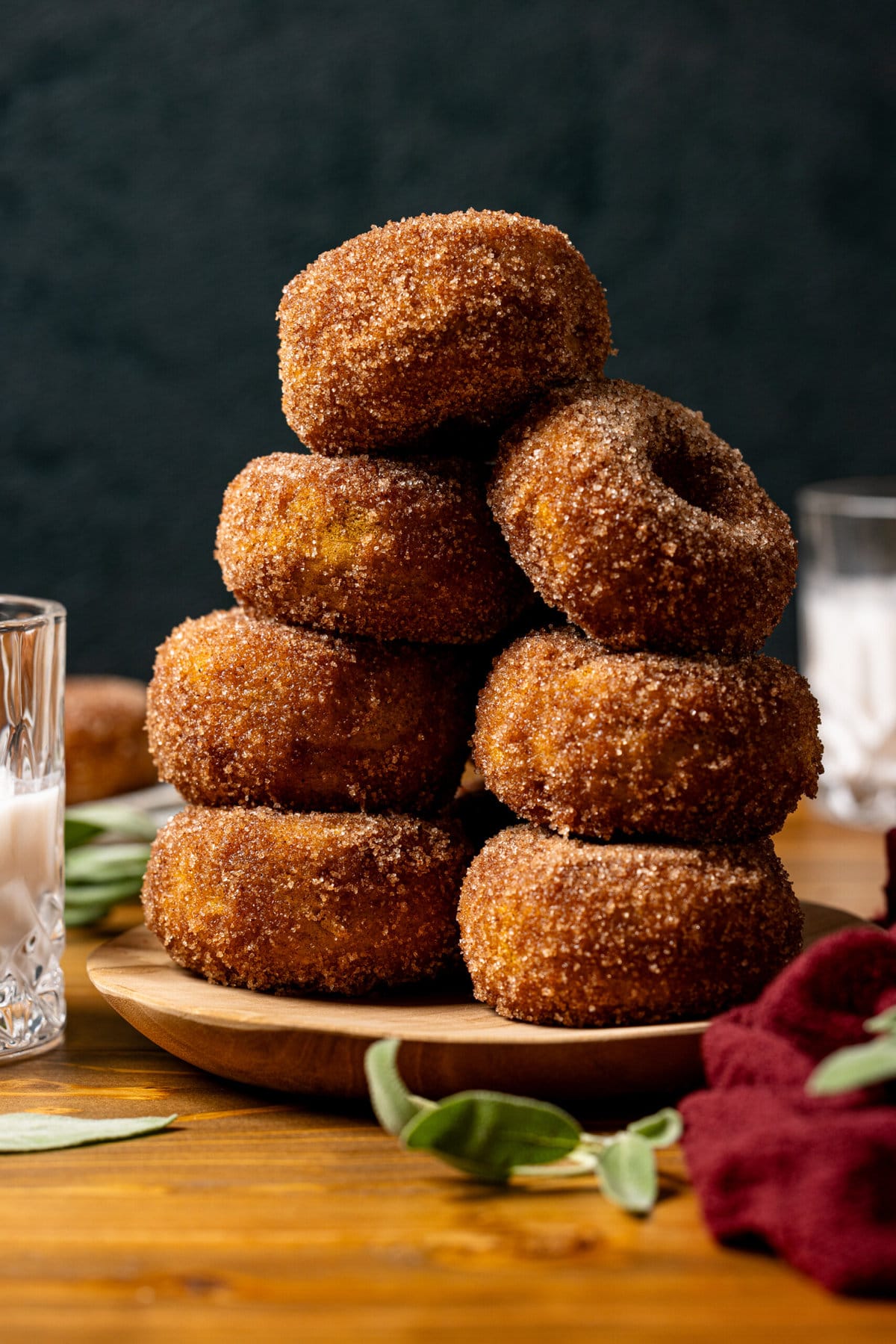 Stacked donuts on a brown plate with glasses of milk.