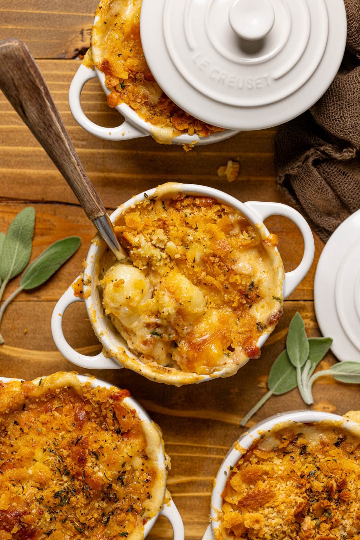 Baked gnocchi in mini cocettes on brown wood table.