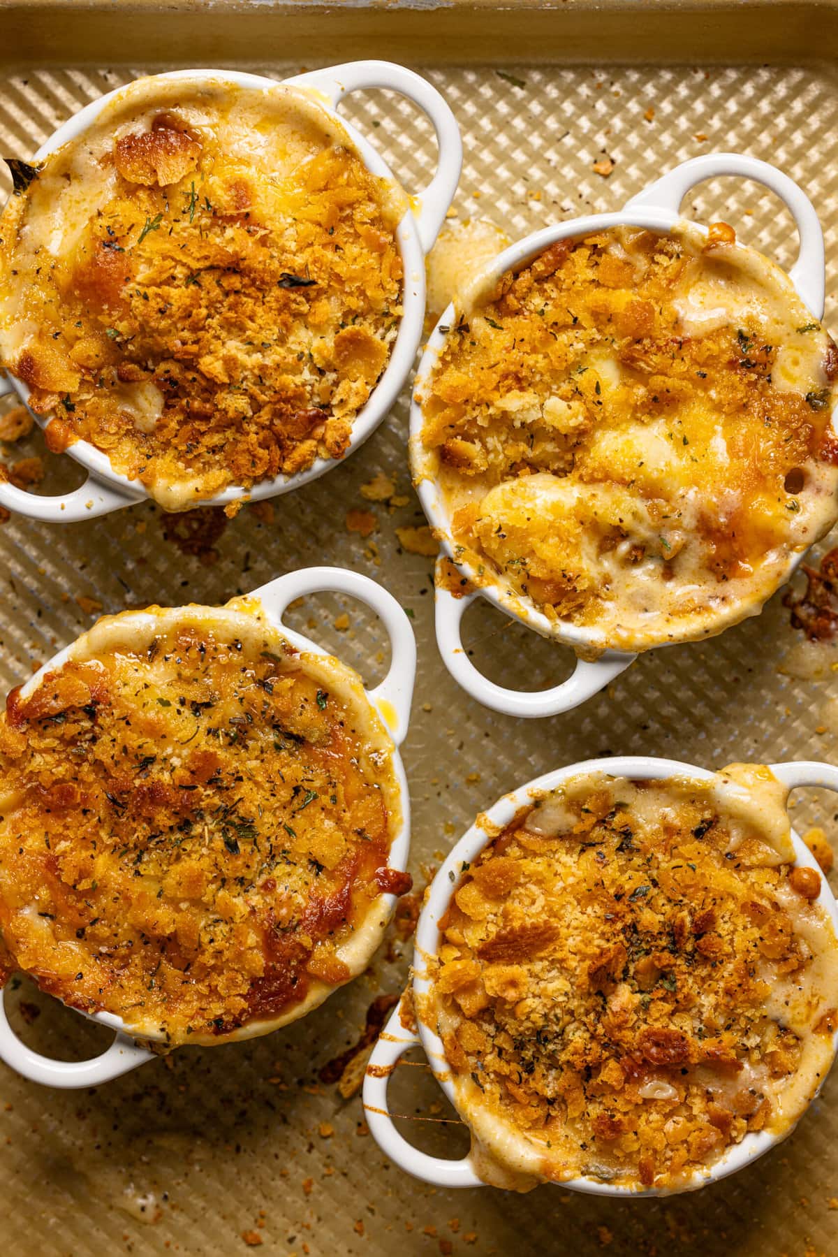 Baked mac and cheese gnocchi in mini cocottes on a baking sheet.