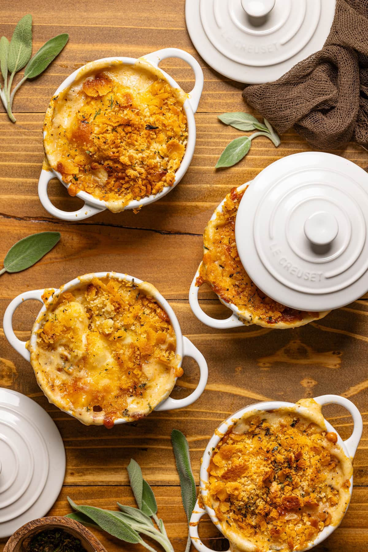 Baked southern mac and cheese gnocchi in mini cocottes on a brown wood table.