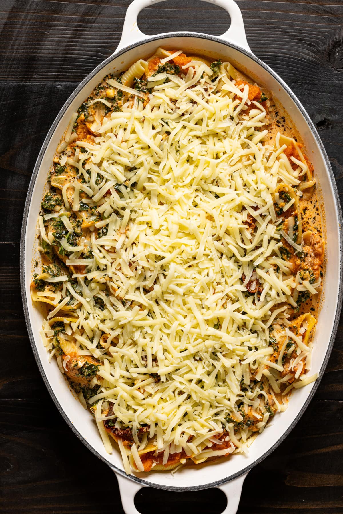 Shells in a baking dish topped with cheese. 