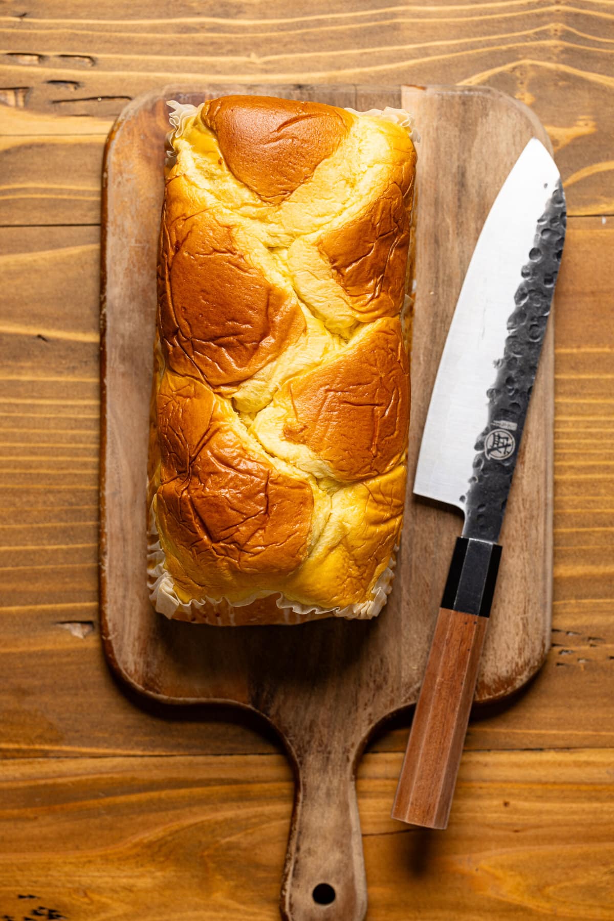 Brioche bread on a cutting board with a knife.