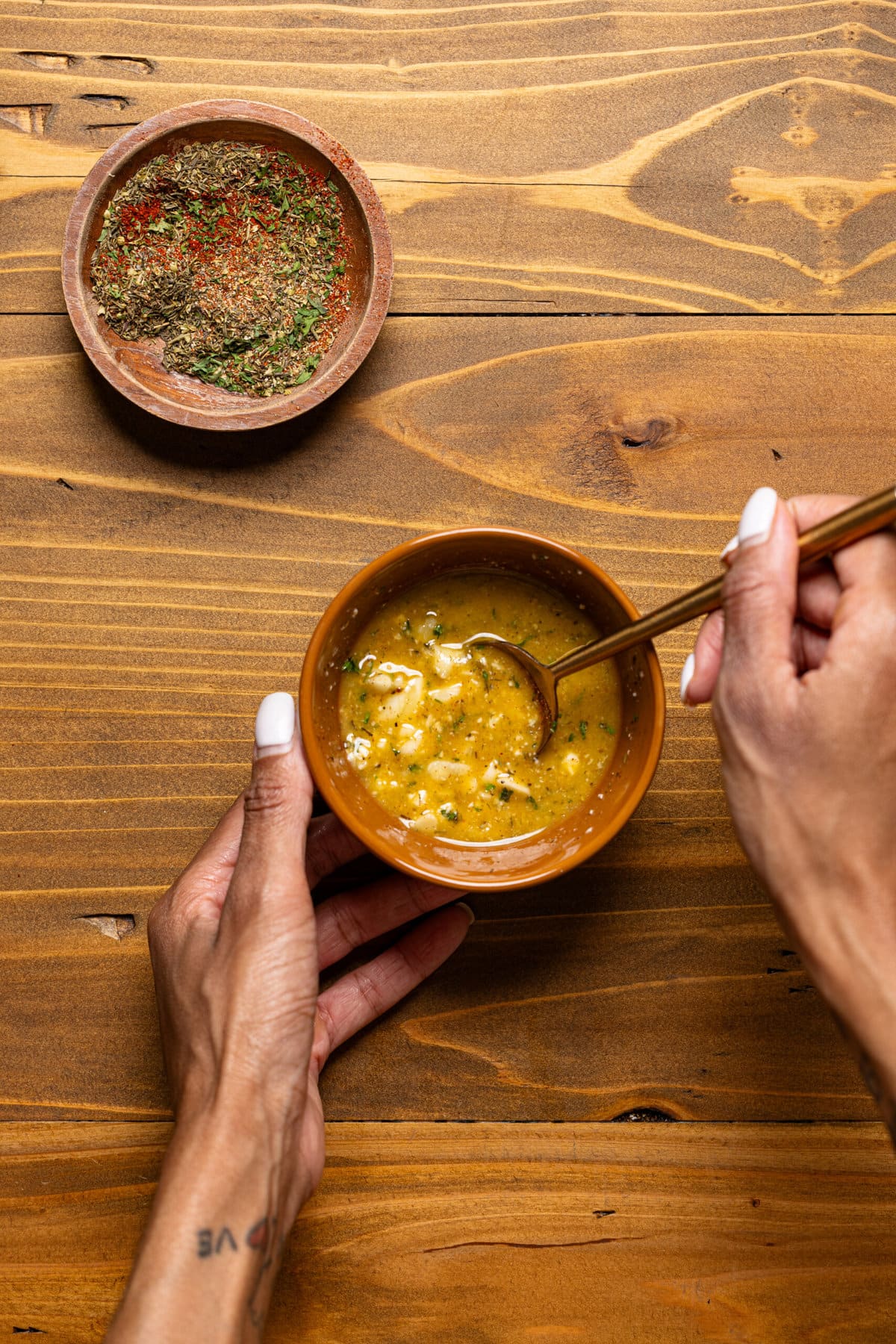 Garlic butter in a bowl being held with a spoon.