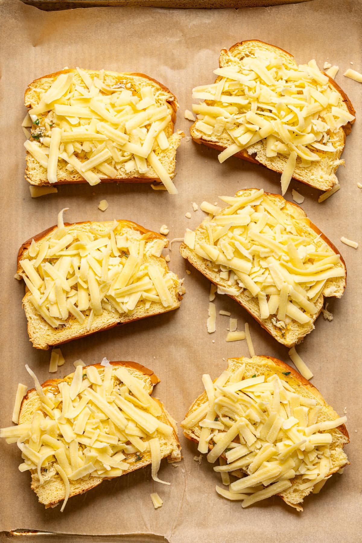 Texas toast Bread lined side by side on a baking sheet with parchment topped with cheese.