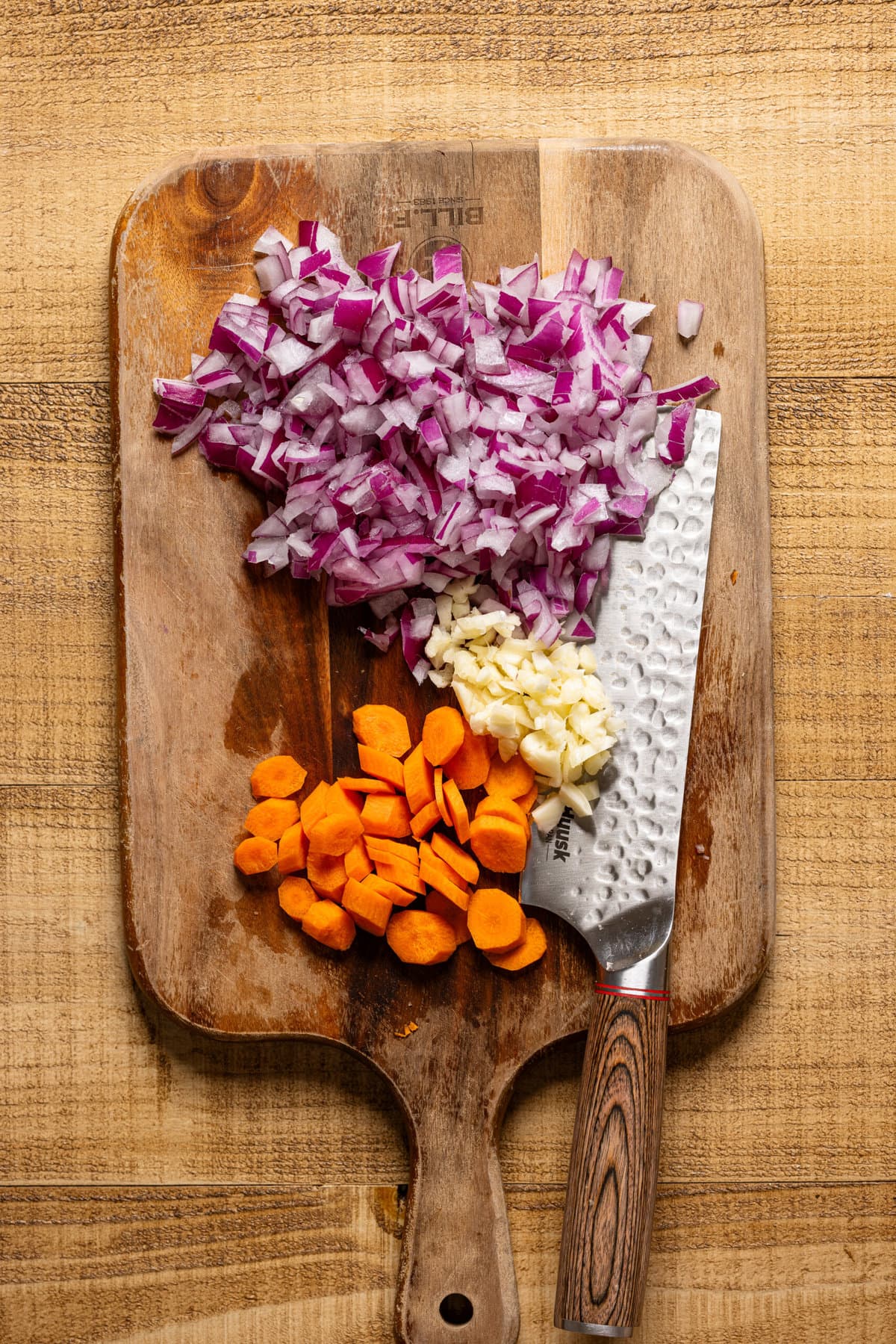 Chopped veggies for the chili recipe on a cutting board with a knife. 