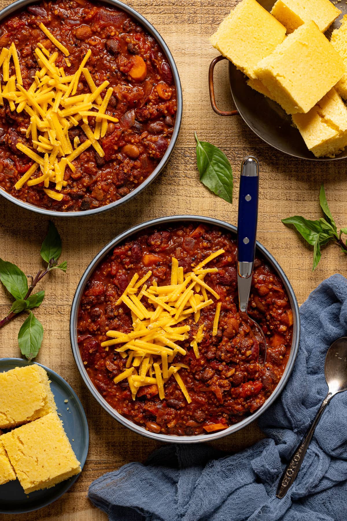 Two bowls of with sides of cornbread in two plates.