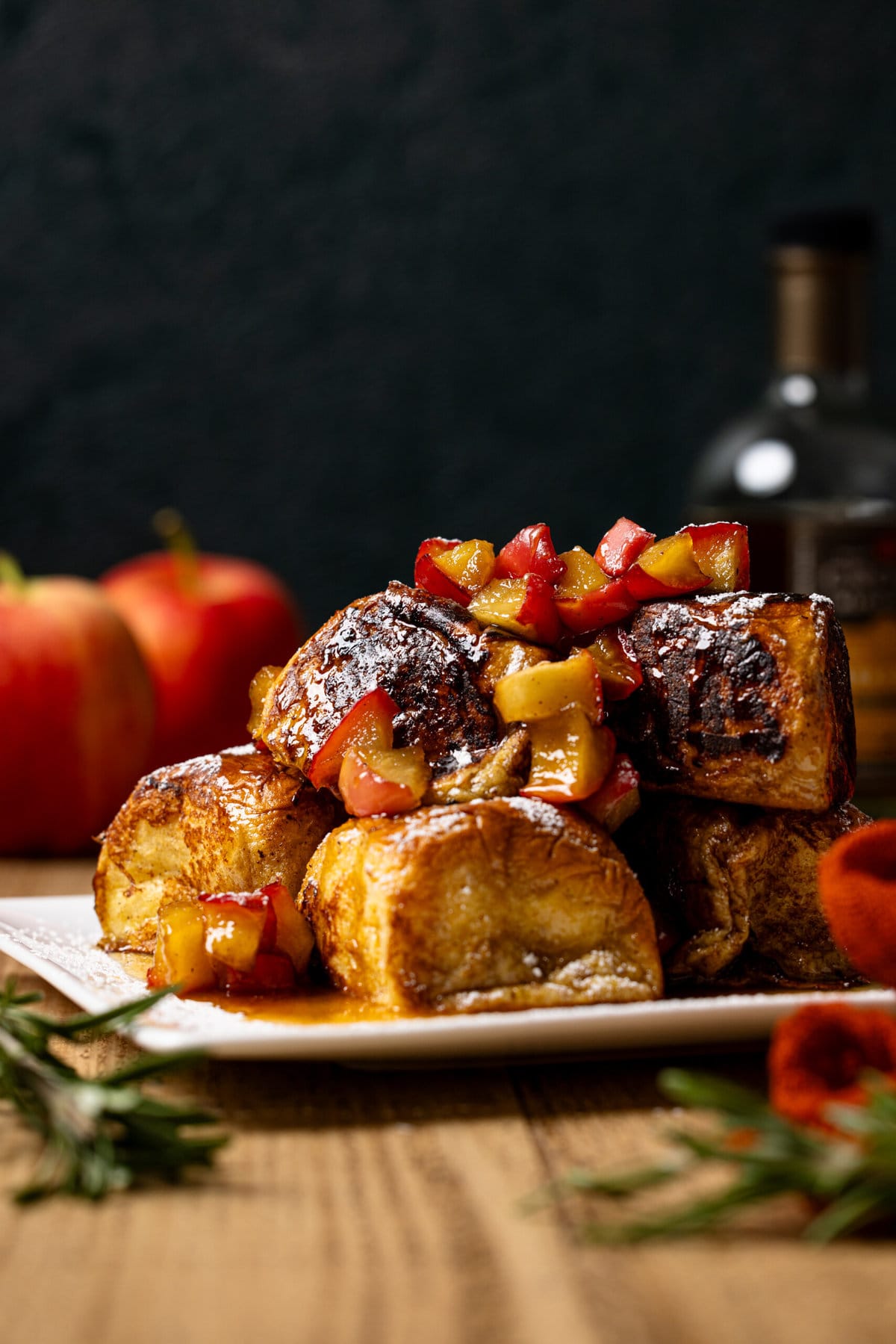 Stacked apple pie french toast with powdered sugar and apples.