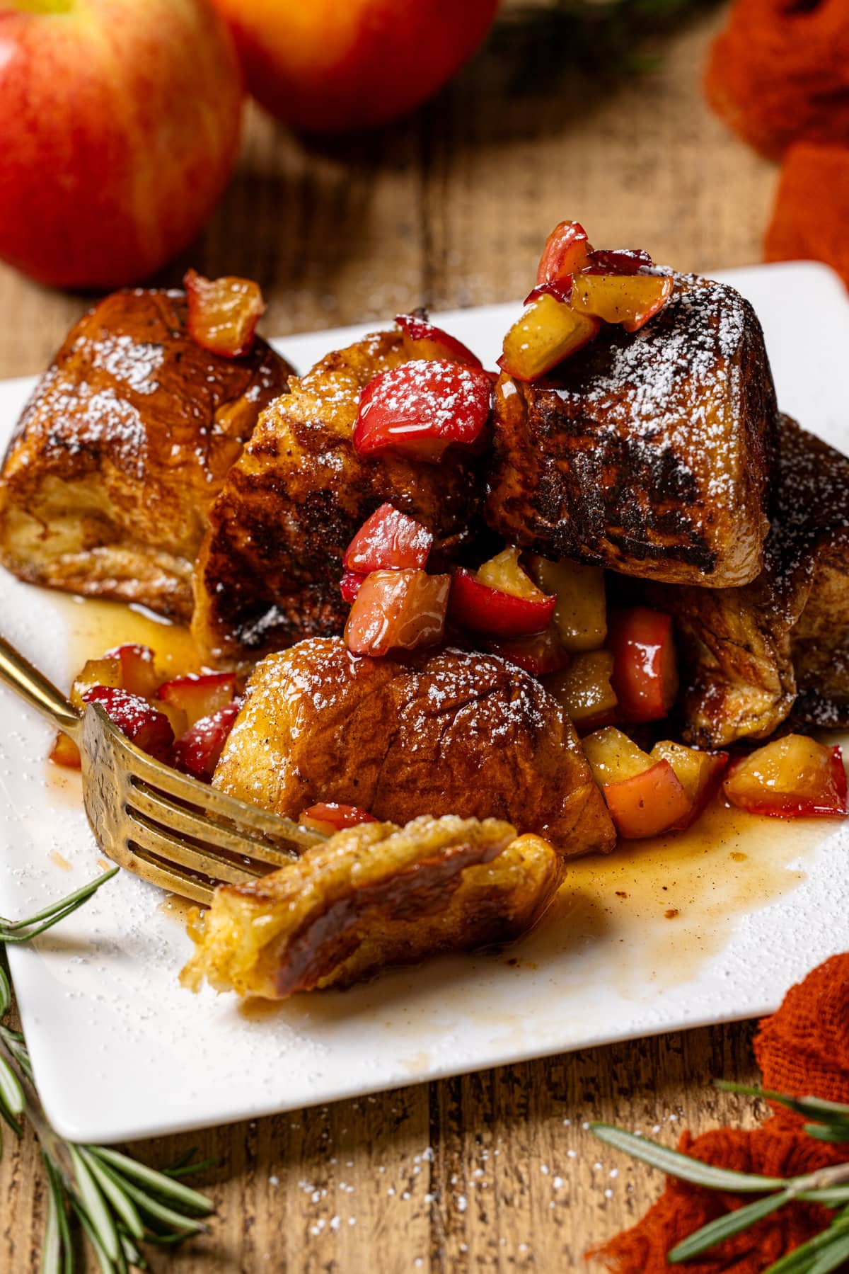 French toast on a white plate with a fork and apples.