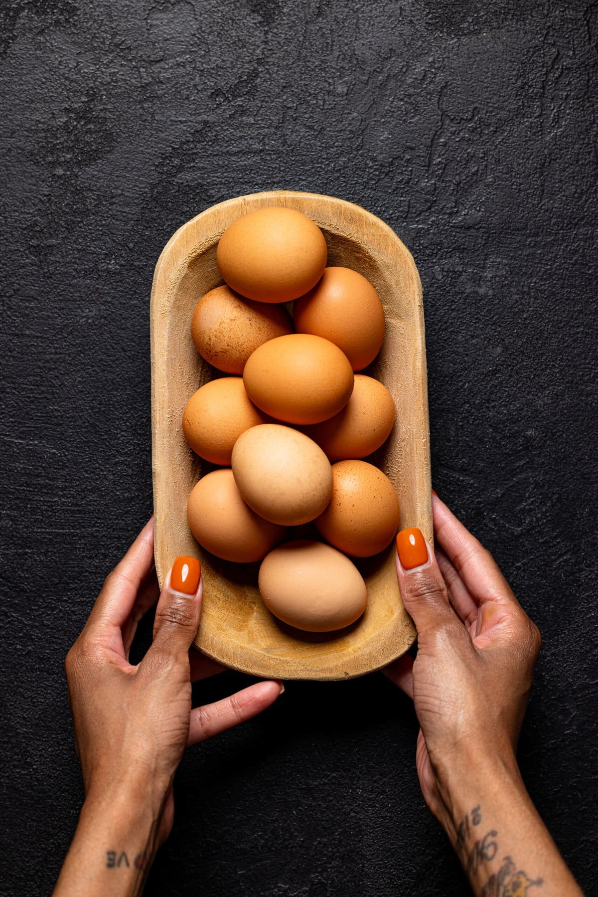 Wooden bowl being held with eggs.