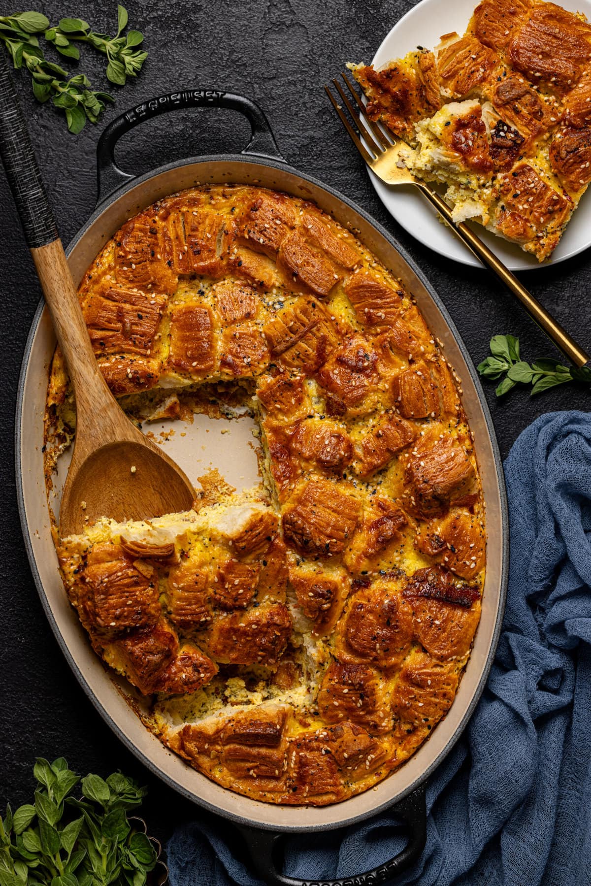 Breakfast casserole cut out of baking dish with a wooden spoon and a plate on the side.