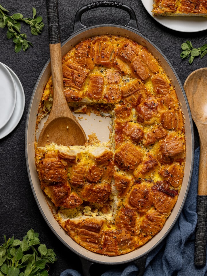 Breakfast casserole cut out of baking dish with a wooden spoon and a plate on the side.