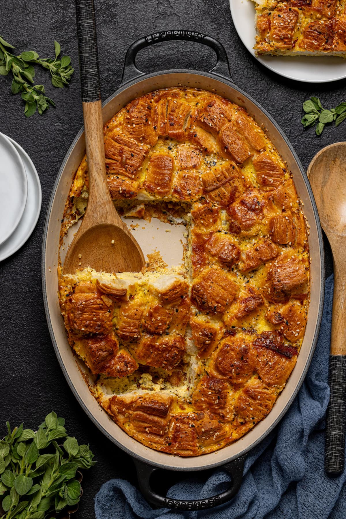 Breakfast casserole cut out of baking dish with a wooden spoon and a plate on the side.
