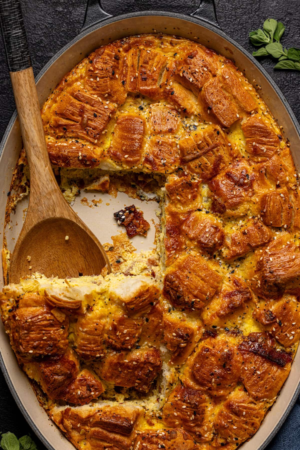 Breakfast casserole on a black baking dish with a wooden spoon.