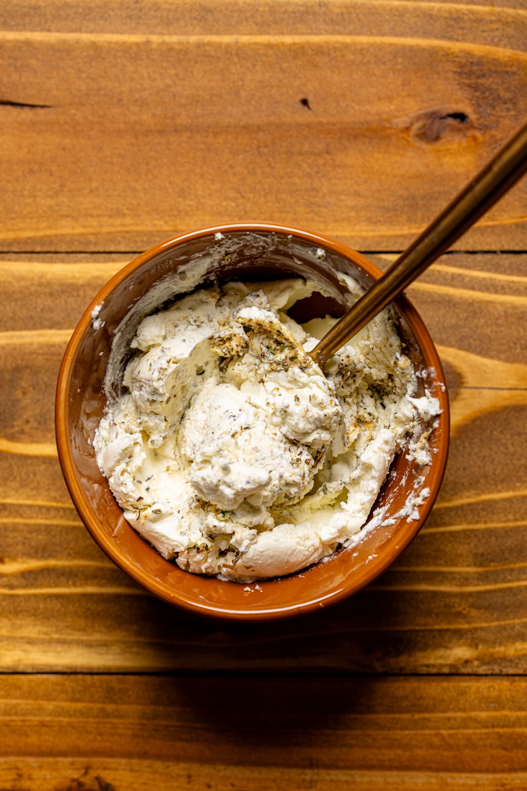 Garlic herb cream cheese in a bowl with a spoon.