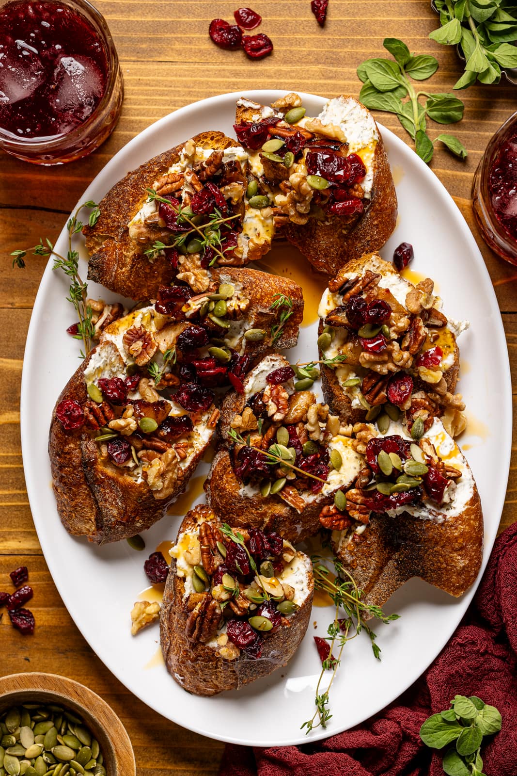 Crostinis on a white platter with a drink, and garnish.